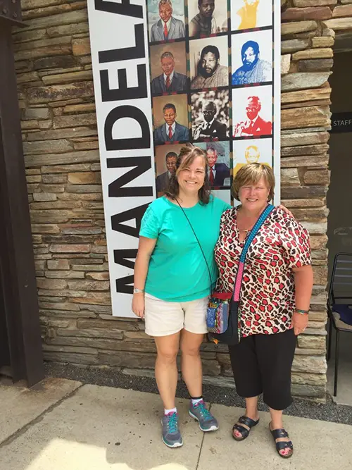 Adoption of Indiana - Two women standing in front of a poster dedicated to Mandela