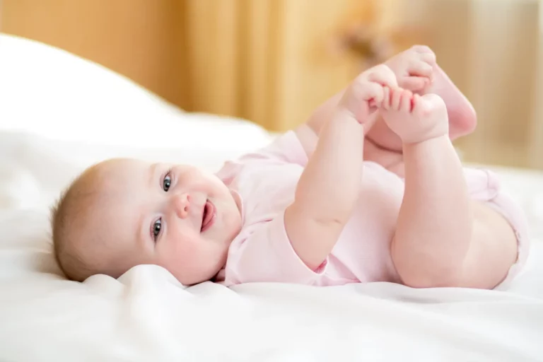 Adoption Grief: Sweet infant girl playing with her feet in a moment of innocence and joy.