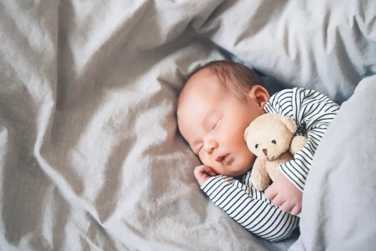 newborn sleeping with teddy bear in a white crib Domestic Infant Adoption
